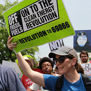 Activist holds sign reading "We are the Clean Energy Revolution"